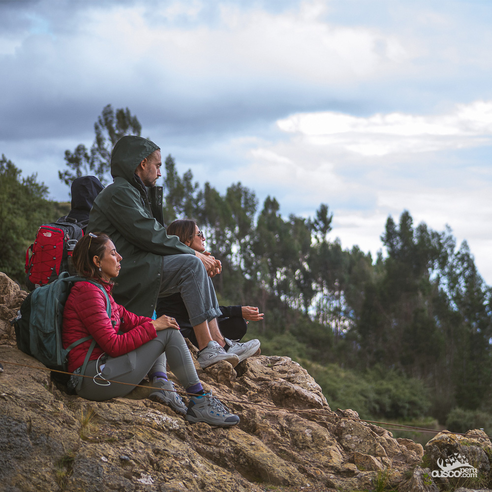 Tourists resting on the slope of a mountain in Cusco, with forest and mountains in the background, avoiding altitude sickness.